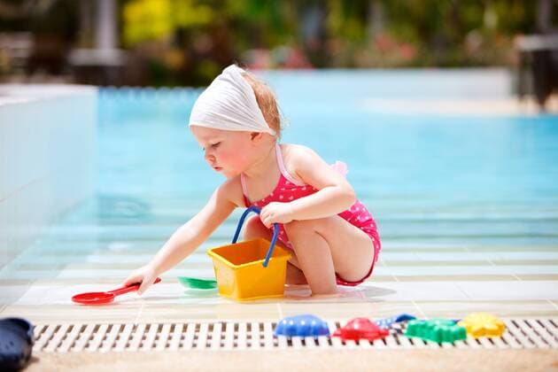 kleines Maedchen spielt im Urlaub an einem Swimmingpool little girl playing at the edge of a swimming pool BLWS269807