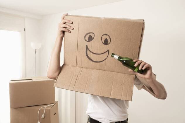 Man wearing happy face moving box over head and pretending to drink beer, Bavaria, Germany mit_2003_02704