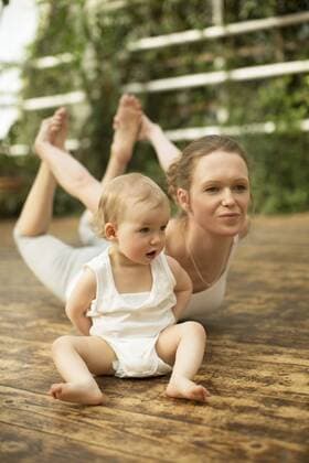 WELLNESS UND GESUNDHEIT Model Released: Junge Mutter macht Yoga Woman doing yoga exercise while baby sitting besides model released Symbolfoto  ABF000636