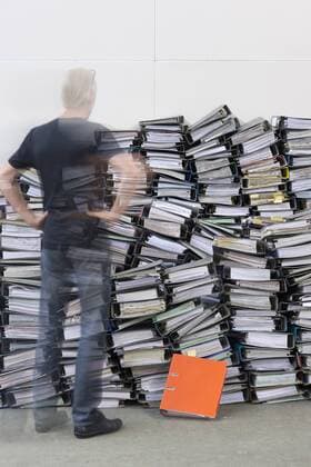 Man standing in front of pile of office files model released Symbolfoto  ASF005670