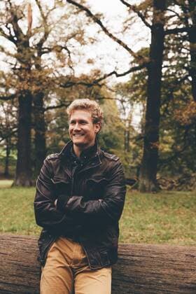 Portrait of smiling young man with crossed arms in autumnal park model released Symbolfoto  CHAF000200