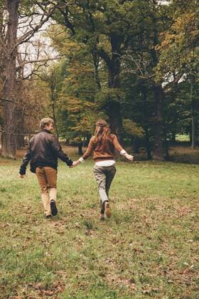 Back view of young couple in love holding hands and running in an autumnal park model released Symbolfoto  CHAF000207