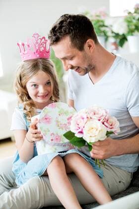 Girl wearing pink crown sitting on father s lap with bunch of flowers model released Symbolfoto property released  WESTF021485