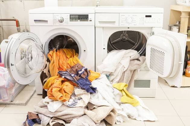 IMAGO Creative: Internationaler Frauentag, Mental Load und Care-Arbeit IMAGO Creative: Haushaltsgeräte - Wäschetrockner Dirty laundry flowing out of washing machine and tumble dryer  JUNF000415