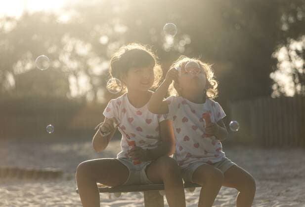 Two little sisters making soap bubbles in the park at twilight model released Symbolfoto  MGOF000483