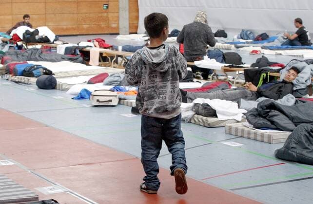 Provisorische Erstaufnahmeeinrichtung fuer Fluechtlinge in der Turnhalle der Reischlesche Wirtschaftsschule in Augsburg mit einem provisorischen Matratzenlager am 18.09.15. Bund und Laender haben nach monatelangem Ringen eine Einigung bei der Kostenverteilung für die Versorgung von Fluechtlingen erzielt. Bei einem mehrstuendigen Treffen im Kanzleramt verstaendigten sich Bundeskanzlerin Angela Merkel (CDU) und die Ministerpraesidenten am spaeten Donnerstagabend (24.09.15) auf eine monatliche Kostenpauschale von 670 Euro pro Fluechtling, die der Bund kuenftig uebernehmen wird. (Siehe epd-Meldung vom 25.09.15) Bund erhoeht Ausgaben für Fluechtlinge Copyright: epd-bild AnnettexZoepf EDITORIAL USE ONLY