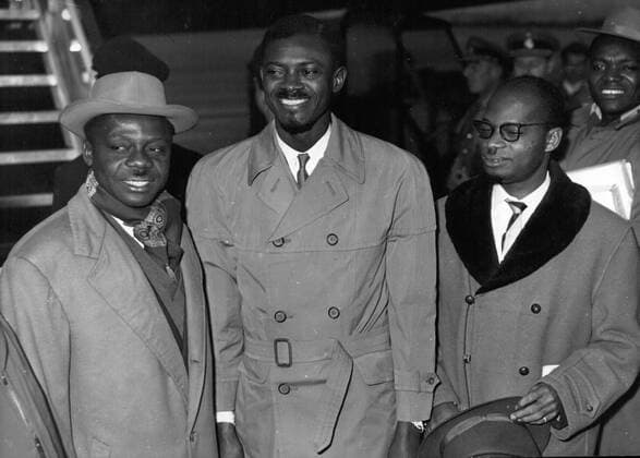 Dec. 26, 1962 - Patrice Lumumba, head of the Mouvement National Congolais arriving for the Round Table Conference in Brussels. Right: ALBERT KALONJI, who would pronounce himself six months later King Albert I of the Kasai, left possibly VICTOR NENDAKA (the original French caption gives no name for the man at left) - ZUMAk09_