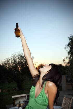 Happy young woman lifting a beer at sunset model released Symbolfoto property released  TOYF001095