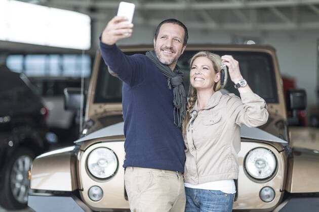 Happy couple at car dealership taking selfie in front of new car model released Symbolfoto property released  ZEF006922