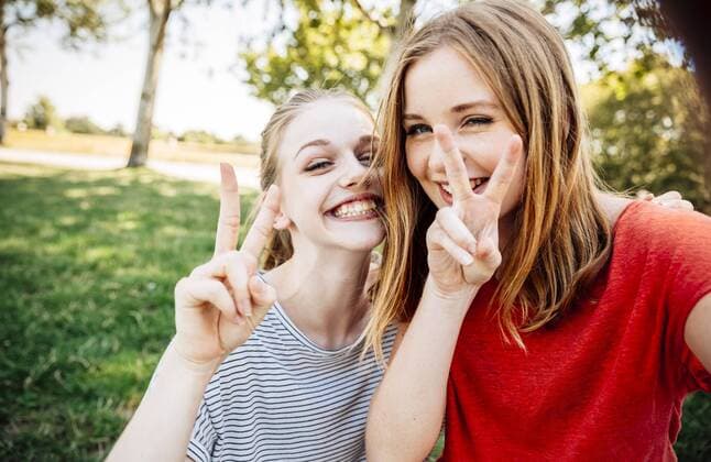 Two playful teenage girls making victory sign model released Symbolfoto  AIF000052