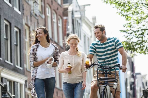 Netherlands, Amsterdam, happy friends with beer bottles and bicycle in the city model released Symbolfoto  FMKF002111