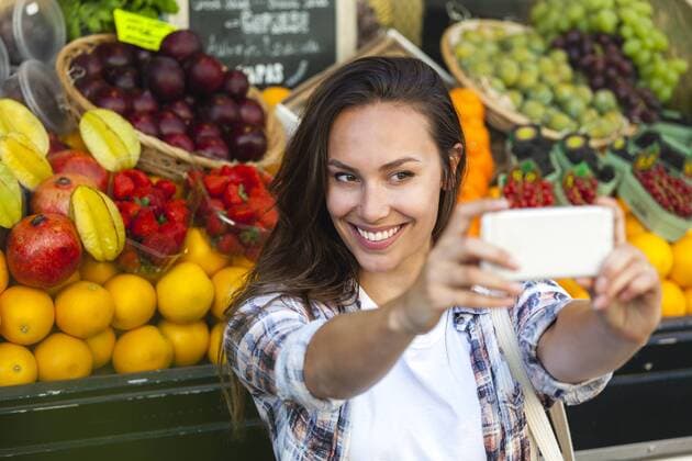 Smiling young woman taking a selfie at greengrocer s shop model released Symbolfoto  FMKF002150