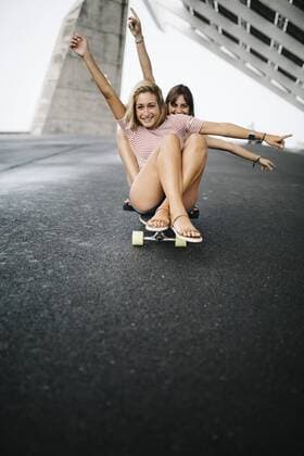 Two young women cruising on a longboard  JRFF000091