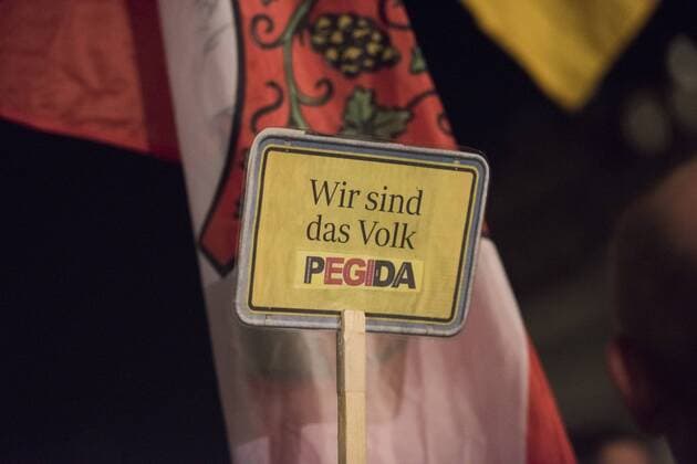 Dresden, Anhaenger des Pegida - Buendnisses (Patriotische Europäer gegen die Islamisierung des Abendlandes) stehen am Montag (02.11.2015) bei einer Kundgebung auf dem Theaterplatz mit einem Schild mit der Aufschrift Wir sind das Volk Pegida .