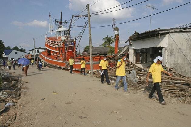 thailand, phang nga district, nam kem, tsunami. volunteers and the locals walk past a fishing boat ploughed into a house. the damage caused by the tsunami, nothing is left standing in the village, about 125kms north of phuket on the 31st dec. Copyright: 904_05_20095038