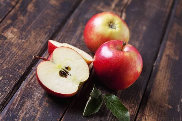 Whole and sliced red apples on dark wood  CSF026644