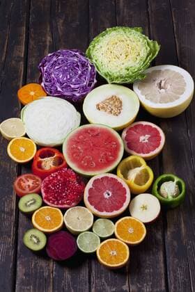 Halves of different vegetables and fruits on dark wood  CSF026670