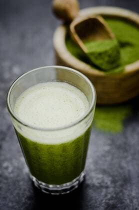 Moringa smoothie with orange and lemon juice, moringa powder in wooden bowl  CZF000225