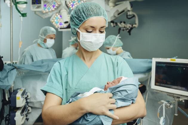 Operating room nurse holding newborn in operating room  MFF002366