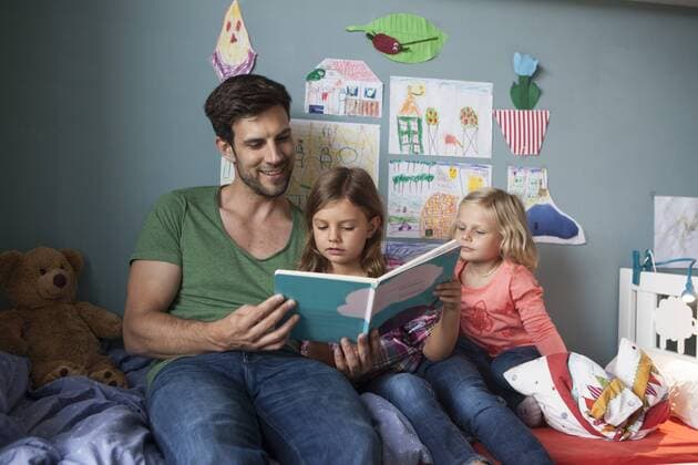 Father and his little daughters sitting together on bed in children s room reading a book model released Symbolfoto property released  RBF003400