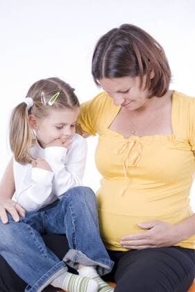 schwangere Mutter mit ihrer Tochter haelt sich liebevoll den Bauch pregnant woman with daughter BLWS241282