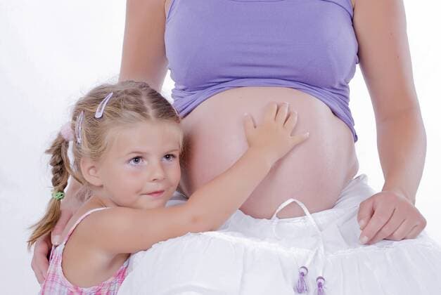 Maedchen beruehrt den Babybauch der Mutter girl touches baby belly of mother BLWS241594