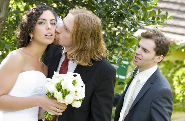 Trauzeuge kuesst Braut, Braeutigam schaut einfersuechtig zu bridal couple and groomsman BLWS242280