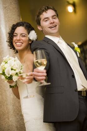 Brautpaar stoesst mit Sektglaesern an bridal couple clinking glasses BLWS242281