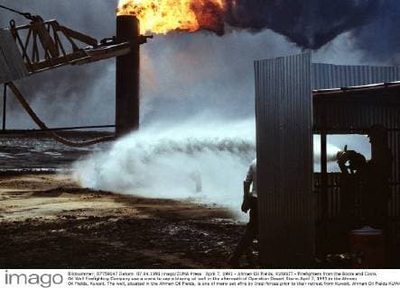 April 7, 1991 - Ahman Oil Fields, KUWAIT - Firefighters from the Boots and Coots Oil Well Firefighting Company use a crane to cap a blazing oil well in the aftermath of Operation Desert Storm April 7, 1991 in the Ahman Oil Fields, Kuwait. The well, situated in the Ahman Oil Fields, is one of many set afire by Iraqi forces prior to their retreat from Kuwait. Ahman Oil Fields KUWAIT - ZUMAp138