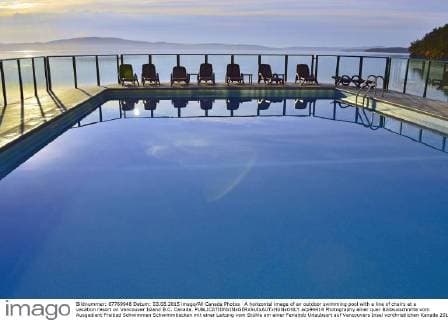 A horizontal image of an outdoor swimming pool with a line of chairs at a vacation resort on Vancouver Island B.C. Canada.  acp94414 Photography