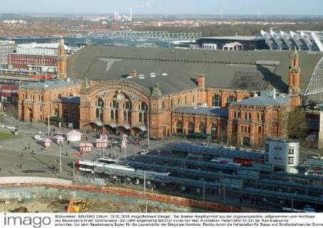 Der Bremer Hauptbahnhof aus der Vogelperspektive, aufgenommen vom Hochhaus des Bausenators in der Contrescarpe. Der 1889 eingeweihte Bahnhof wurde von dem Architekten Hubert Stier im Stil der Neorenaissance entworfen. Vor dem Haupteingang Buden für die Losverkäufer der Bürgerparktombola. Rechts davon die Haltestellen für Busse und Straßenbahnen der Bremer Straßenbahn AG (BSAG). Im Vordergrund die Baustelle für ein Geschäftsgebäude-Komplex der Hamburger Achim-Griese-Treuhandgesellschaft, entworfen von dem Architekten Max Dudler. Hinten rechts die Betonpfeiler der Bremer Stadthalle (ÖVB-Arena), links daneben das Congress Centrum Bremen und die Messehallen.