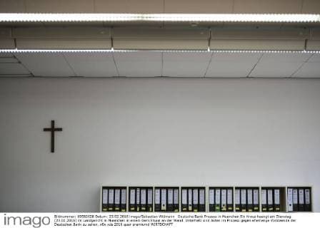 Deutsche Bank Prozess in Muenchen Ein Kreuz haengt am Dienstag (23.02.2016) im Landgericht in Muenchen in einem Gerichtsaal an der Wand. Unterhalb sind Akten im Prozess gegen ehemalige Vorstaende der Deutschen Bank zu sehen.