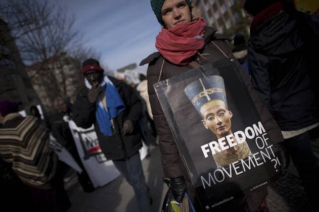 Gedenkmarsch Kolonialgeschichte DEU, Deutschland, Germany, Berlin, 27.02.2016 Demonstrant mit Plakat Freedom of Movement und Foto der Nofretete gegen die Kolobialgeschichte und die Aneigung afrikanischer Kulturgueter durch deutsche Museen und dem Humboldt Forum beim 10. Gedenkmarsch zur Erinnerung an die afrikanischen Opfer von Versklavung, Kolonialismus und rassistischer Gewalt vom Komitee fuer ein afrikanisches Denkmal in Berlin und afrikanischer Vereine in Berlin. Dieser Gedenkmarsch wurde ins Leben gerufen, um der Forderung nach Anerkennung der Verbrechen gegen Schwarze Menschen und Menschen afrikanischer Herkunft Nachdruck zu verleihen. Anlass ist die Berliner Afrika-Konferenz von 1884 - 1885, auf der Afrika vor 130 Jahren unter den europaeischen Kolonialmaechten aufgeteilt wurde. Mehr als 30 Millionen Afrikanerinnen und Afrikaner wurden Opfer von Versklavung und kolonialen Verbrech