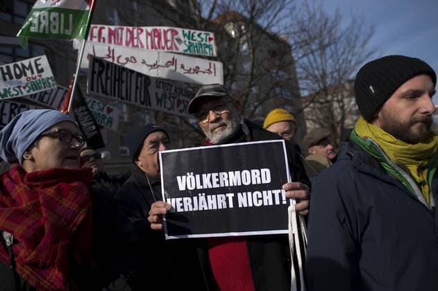 Gedenkmarsch Kolonialgeschichte DEU, Deutschland, Germany, Berlin, 27.02.2016 Demonstranten mit Plakat Voelkermord verjaehrt nicht und Set them Free beim 10. Gedenkmarsch zur Erinnerung an die afrikanischen Opfer von Versklavung, Kolonialismus und rassistischer Gewalt vom Komitee fuer ein afrikanisches Denkmal in Berlin und afrikanischer Vereine in Berlin. Dieser Gedenkmarsch wurde ins Leben gerufen, um der Forderung nach Anerkennung der Verbrechen gegen Schwarze Menschen und Menschen afrikanischer Herkunft Nachdruck zu verleihen. Anlass ist die Berliner Afrika-Konferenz von 1884 - 1885, auf der Afrika vor 130 Jahren unter den europaeischen Kolonialmaechten aufgeteilt wurde. Mehr als 30 Millionen Afrikanerinnen und Afrikaner wurden Opfer von Versklavung und kolonialen Verbrechen gegen die Menschlichkeit. Die von Deutschland an den Herero und Nama begangenen Voelkermorde in Namibia und di