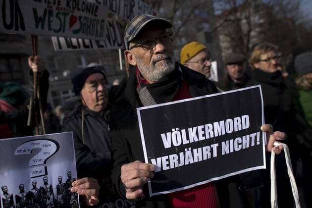 Gedenkmarsch Kolonialgeschichte DEU, Deutschland, Germany, Berlin, 27.02.2016 Demonstranten mit Plakat Voelkermord verjaehrt nicht und Set them Free beim 10. Gedenkmarsch zur Erinnerung an die afrikanischen Opfer von Versklavung, Kolonialismus und rassistischer Gewalt vom Komitee fuer ein afrikanisches Denkmal in Berlin und afrikanischer Vereine in Berlin. Dieser Gedenkmarsch wurde ins Leben gerufen, um der Forderung nach Anerkennung der Verbrechen gegen Schwarze Menschen und Menschen afrikanischer Herkunft Nachdruck zu verleihen. Anlass ist die Berliner Afrika-Konferenz von 1884 - 1885, auf der Afrika vor 130 Jahren unter den europaeischen Kolonialmaechten aufgeteilt wurde. Mehr als 30 Millionen Afrikanerinnen und Afrikaner wurden Opfer von Versklavung und kolonialen Verbrechen gegen die Menschlichkeit. Die von Deutschland an den Herero und Nama begangenen Voelkermorde in Namibia und di