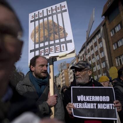Gedenkmarsch Kolonialgeschichte DEU, Deutschland, Germany, Berlin, 27.02.2016 Demonstranten mit Plakat Voelkermord verjaehrt nicht und Set them Free beim 10. Gedenkmarsch zur Erinnerung an die afrikanischen Opfer von Versklavung, Kolonialismus und rassistischer Gewalt vom Komitee fuer ein afrikanisches Denkmal in Berlin und afrikanischer Vereine in Berlin. Dieser Gedenkmarsch wurde ins Leben gerufen, um der Forderung nach Anerkennung der Verbrechen gegen Schwarze Menschen und Menschen afrikanischer Herkunft Nachdruck zu verleihen. Anlass ist die Berliner Afrika-Konferenz von 1884 - 1885, auf der Afrika vor 130 Jahren unter den europaeischen Kolonialmaechten aufgeteilt wurde. Mehr als 30 Millionen Afrikanerinnen und Afrikaner wurden Opfer von Versklavung und kolonialen Verbrechen gegen die Menschlichkeit. Die von Deutschland an den Herero und Nama begangenen Voelkermorde in Namibia und di