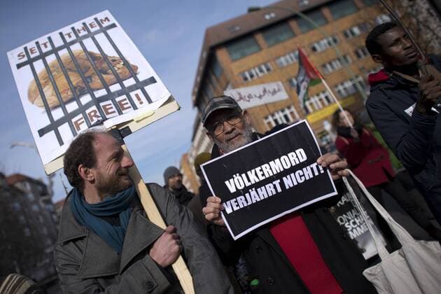 Gedenkmarsch Kolonialgeschichte DEU, Deutschland, Germany, Berlin, 27.02.2016 Demonstranten mit Plakat Voelkermord verjaehrt nicht und Set them Free beim 10. Gedenkmarsch zur Erinnerung an die afrikanischen Opfer von Versklavung, Kolonialismus und rassistischer Gewalt vom Komitee fuer ein afrikanisches Denkmal in Berlin und afrikanischer Vereine in Berlin. Dieser Gedenkmarsch wurde ins Leben gerufen, um der Forderung nach Anerkennung der Verbrechen gegen Schwarze Menschen und Menschen afrikanischer Herkunft Nachdruck zu verleihen. Anlass ist die Berliner Afrika-Konferenz von 1884 - 1885, auf der Afrika vor 130 Jahren unter den europaeischen Kolonialmaechten aufgeteilt wurde. Mehr als 30 Millionen Afrikanerinnen und Afrikaner wurden Opfer von Versklavung und kolonialen Verbrechen gegen die Menschlichkeit. Die von Deutschland an den Herero und Nama begangenen Voelkermorde in Namibia und di