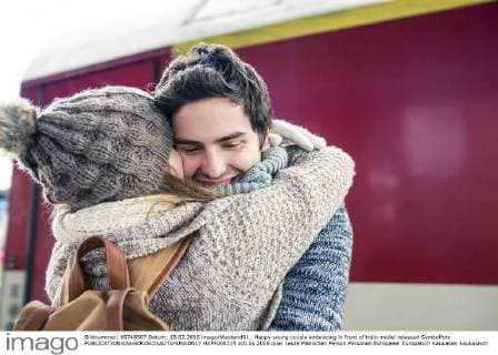 IMAGO Creative: Countdown bis Weihnachten, Nach Hause reisen Happy young couple embracing in front of train model released Symbolfoto  HAPF000215