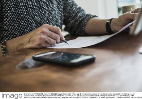Close-up of woman signing document on table model released Symbolfoto property released  UUF006420