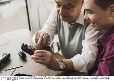 Senior man and grandson with toy train at home model released Symbolfoto property released  UUF006582