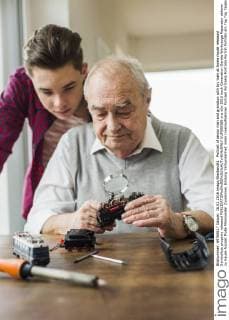 Portrait of senior man and grandson with toy train at home model released Symbolfoto property released  UUF006586