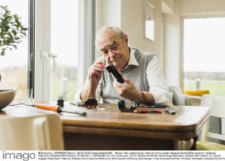 Senior man repairing toy train at home model released Symbolfoto property released  UUF006589