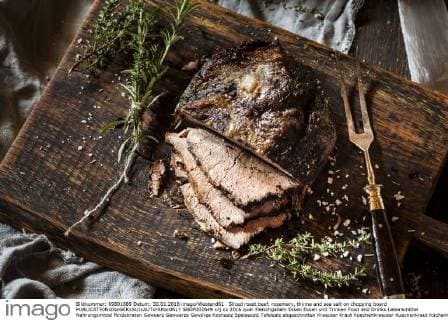 Sliced roast beef, rosemary, thyme and sea salt on chopping board  SBDF002649