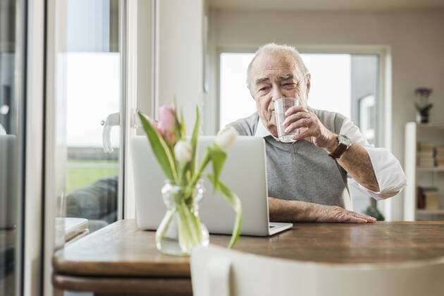 Portrait of senior man with laptop drinking glass of water at home model released Symbolfoto property released  UUF006606