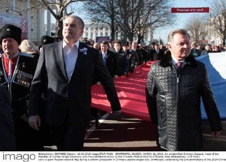 SIMFEROPOL, RUSSIA. MARCH 16, 2016. An unidentified Crimean Cossack, head of the Republic of Crimea Sergei Aksyonov, and the presidential envoy to the Crimean Federal District of Russia, Oleg Belaventsev, (L-R front) carry a giant Russian national flag during a solemn procession in Crimea s second largest city, Simferopol, celebrating the 2nd anniversary of the 2014 Crimean referendum in which 96% of voters supported reunification with Russia. Alexei Pavlishak TASS  TS019971