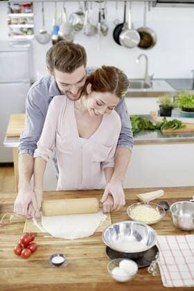 Affectionate couple preparing pizza dough in kitchen model released Symbolfoto property released  FMKF002360