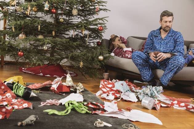 Tired couple in Christmas pyjamas looking at mess of wrapping paper model released Symbolfoto property released  MFF002787