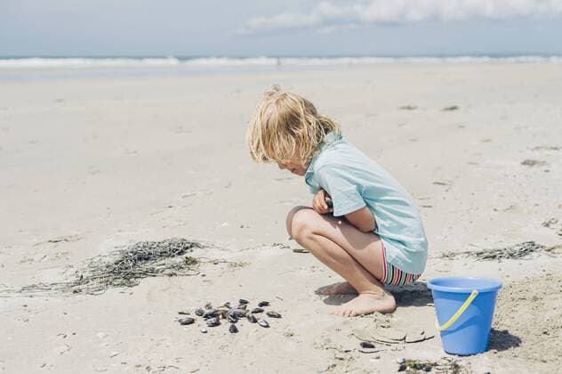 France, Brittany, Finistere, Pointe de la Torche, boy playing with seashells on the beach model released Symbolfoto  MJF001785