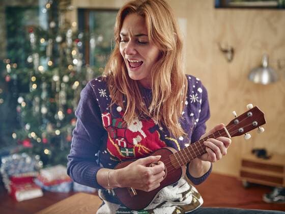 Blond woman playing ukulele in front of Christmas tree model released Symbolfoto property released  RHF001350