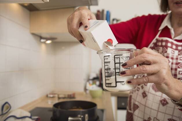 Senior woman filling icing sugar into a measuring cup in kitchen, Munich, Bavaria, Germany mit_2002_08442